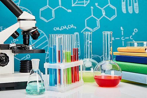 microscope, books, glass test tubes and flasks with colorful liquid on blue background with molecular structure