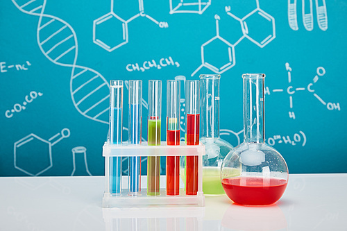 glass test tubes and flasks with colorful liquid on blue background with molecular structure