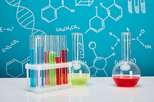 glass test tubes and flasks with colorful liquid on blue background with molecular structure