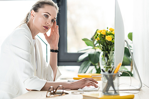 side view of pensive businesswoman at workplace with computer screen in office