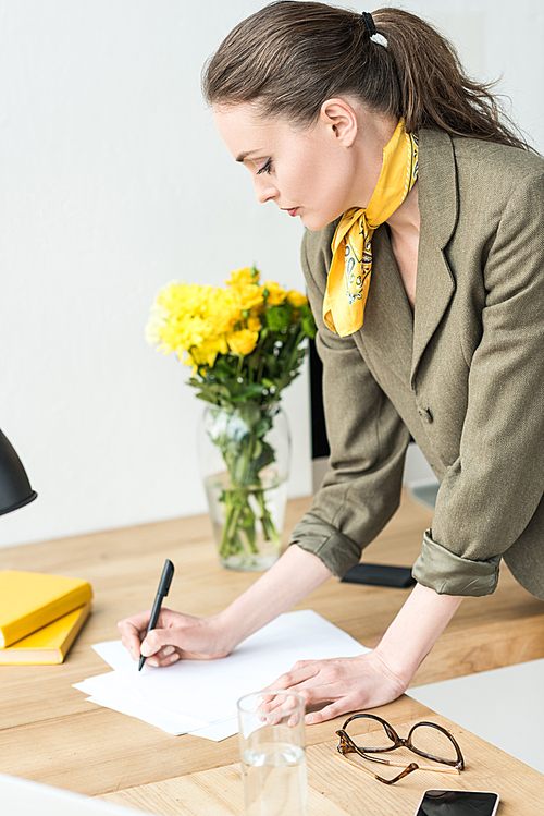 attractive stylish businesswoman taking notes at workplace