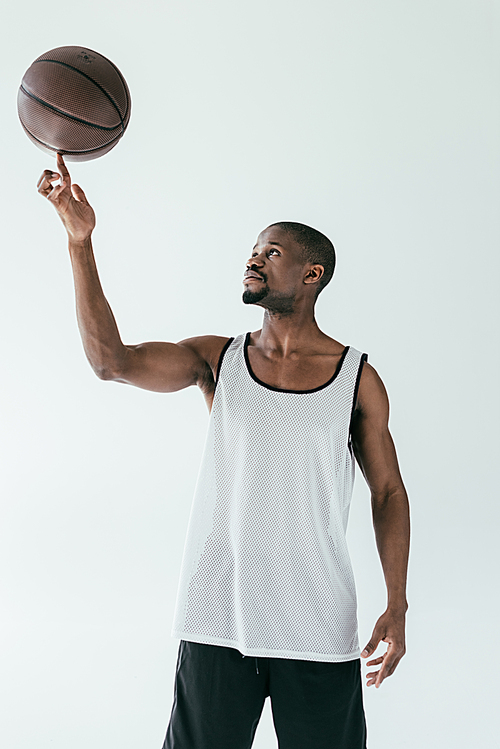 athletic african american basketball player spinning ball on finger, isolated on white