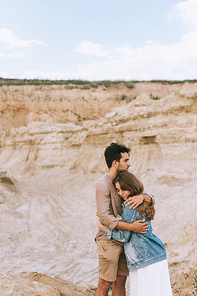 happy boyfriend hugging his beautiful girlfriend in sand canyon