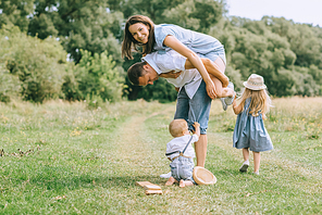 happy family with two kids spending time on summer feild, father piggybacking mom