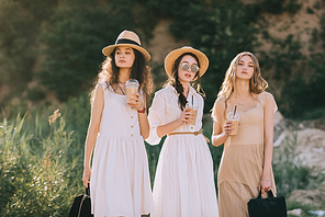 beautiful girls in stylish straw hats holding coffee latte