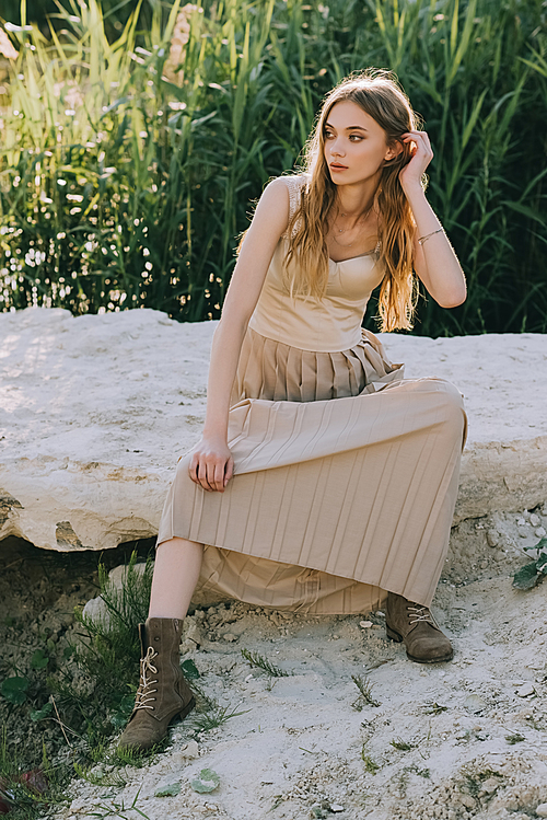 attractive blonde girl in elegant dress sitting on ground