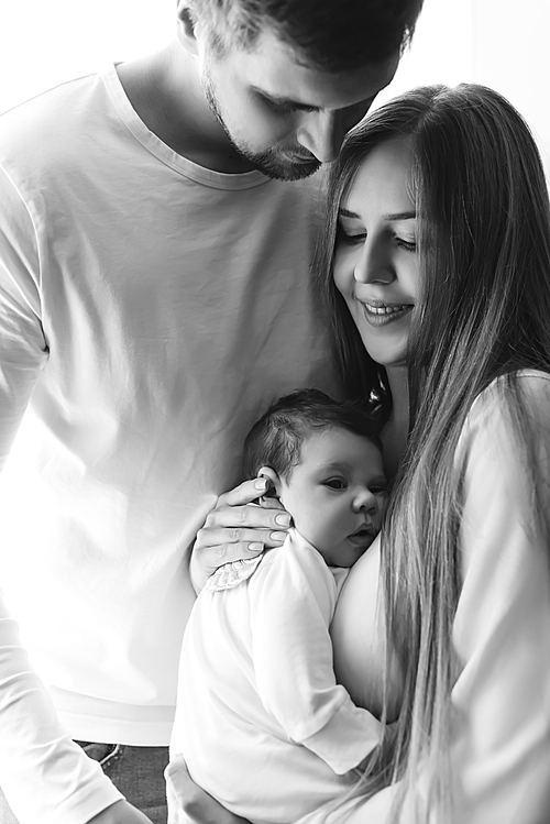 black and white portrait of cheerful family carrying infant son at home