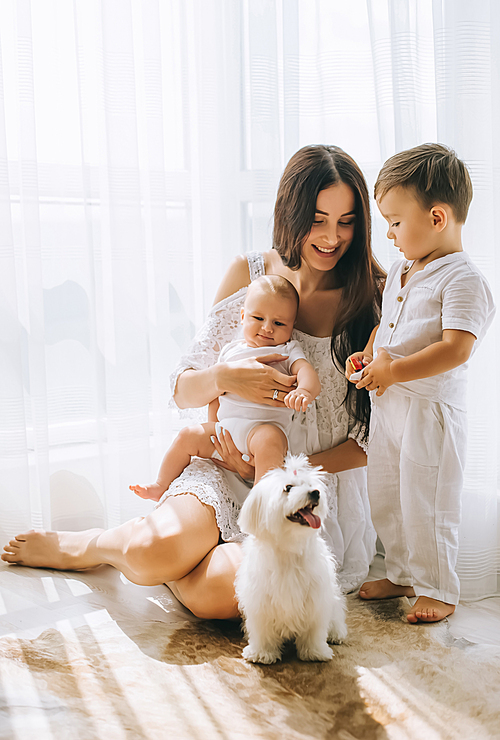 young happy mother spending time with kids and bichon dog