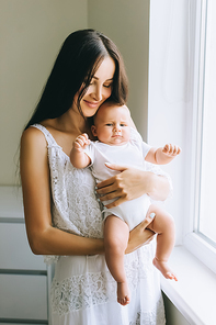 happy young mother carrying her little baby boy at home