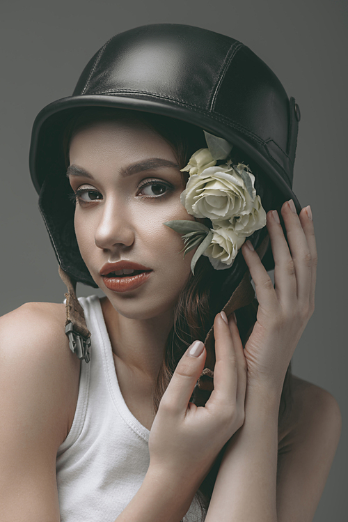 tender girl in military helmet with flowers, isolated on grey