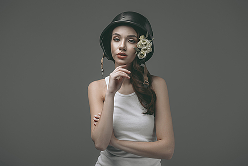 beautiful young girl in military helmet with flowers, isolated on grey