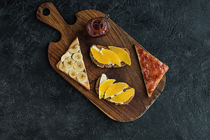 flat lay with snacks for healthy breakfast on wooden cutting board on dark tabletop