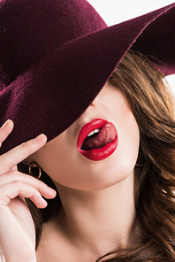 sexy woman sticking tongue out and hiding eyes under burgundy hat