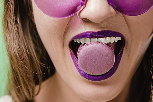 cropped image of girl with purple lips biting macaron