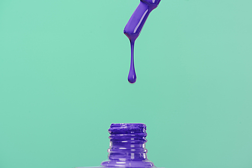 nail polish pouring down into bottle isolated on turquoise