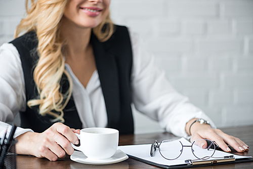 cropped image of businesswoman with cup of coffee