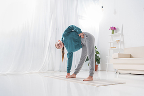 girl stretching on yoga mat at home