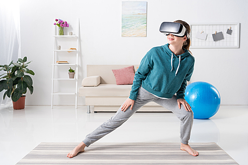 girl stretching legs with virtual reality headset on yoga mat at home