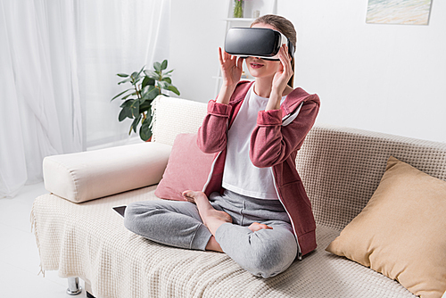 girl sitting in lotus position with virtual reality headset at home