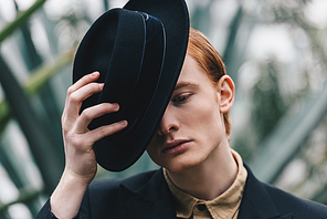 pensive handsome young red-haired man wearing black hat