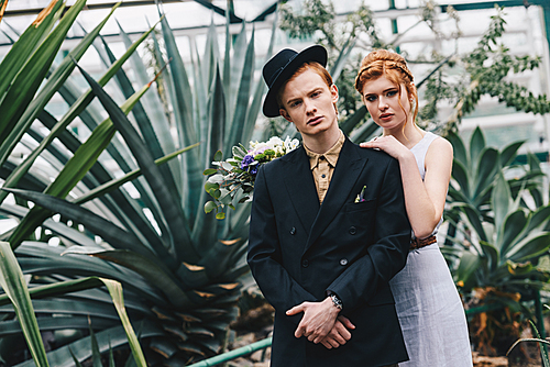 stylish young red-haired wedding couple  in botanical garden
