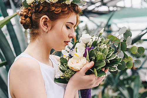 profile portrait of beautiful young red-haired bride holding wedding bouquet