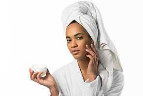 african american woman in bathrobe and towel applying face cream,  isolated on white
