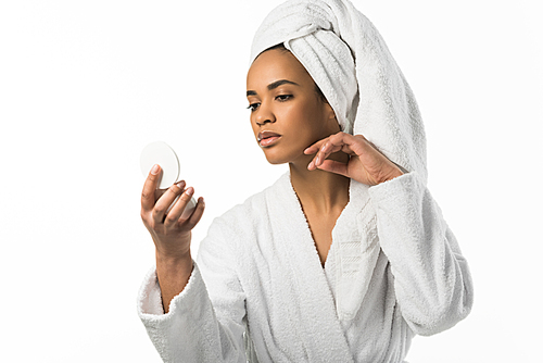 african american woman in bathrobe and towel looking at mirror at her clean skin,  isolated on white