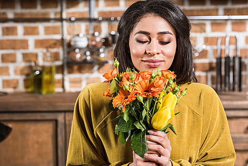 beautiful happy young woman with closed eyes holding bouquet of flowers at home