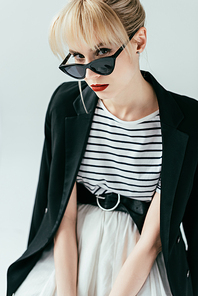 Fashionable blonde girl in sunglasses posing isolated on grey