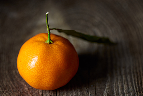 selective focus of fresh tangerine with green leaf on wooden table