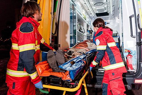 Paramedics transportating patient on gurney in ambulance car