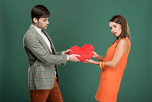 beautiful couple holding heart shaped pillow isolated on green