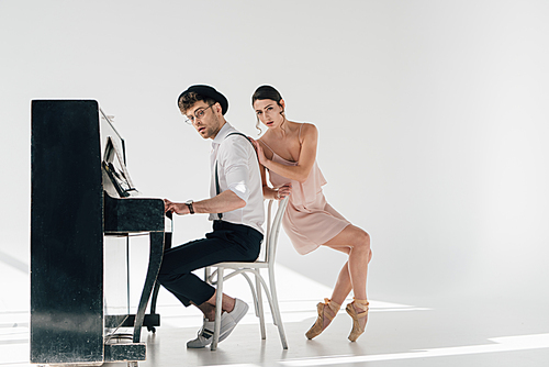 attractive ballerina touching handsome musician playing piano