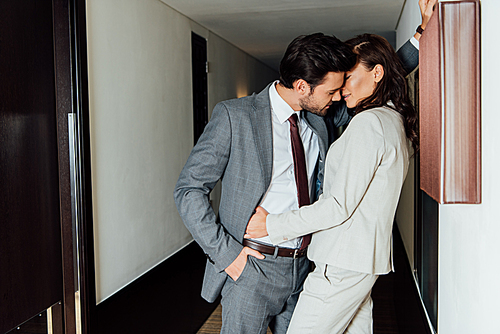 handsome man in suit stand with hand in pocket and  attractive woman in hotel corridor