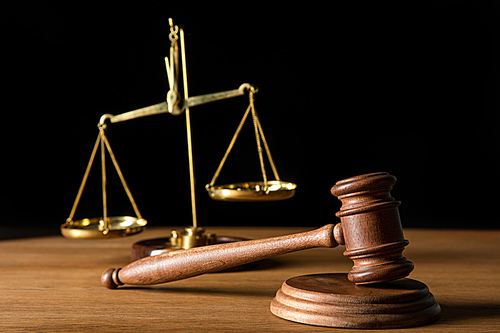 selective focus of vintage golden scales and gavel on wooden table isolated on black