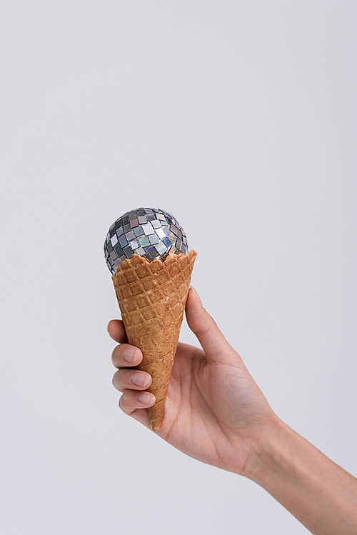 cropped shot of ice cream cone with christmas ball in hand isolated on grey