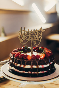 Happy Birthday sign on chocolate cake with fruits