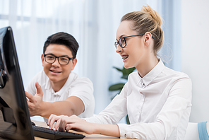 young happy students pointing on screen of computer