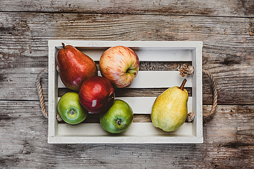 elevated view of apples and pears in wooden box on rustic table