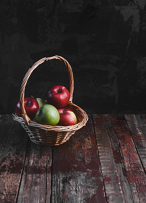 pile of apples in wicker basket on rustic wooden table