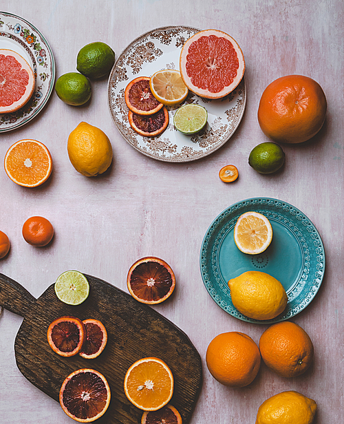 top view of plates, cutting board and different citrus fruits on table