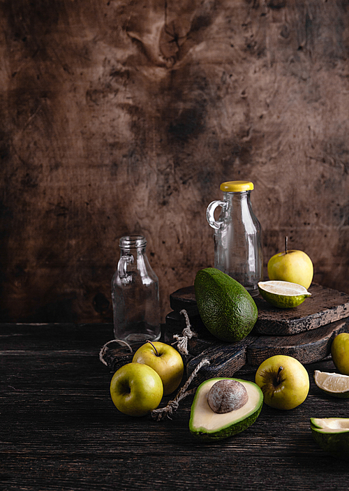Glass bottles and fruit ingredients for smoothie on rustic wooden board
