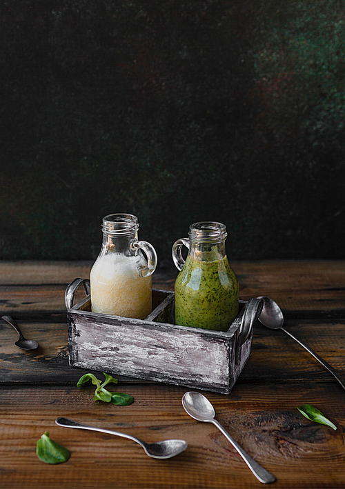 Organic green and white smoothies on wooden background