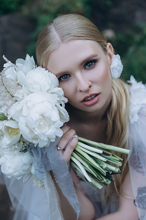 close-up portrait of beautiful young bride in dress with bouquet 