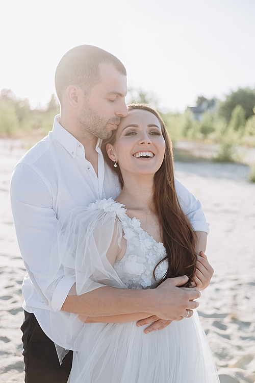 beautiful happy stylish couple hugging on beach