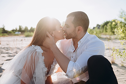 beautiful happy couple kissing on beach with back light