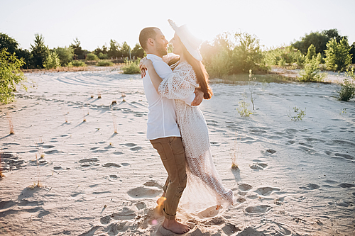 beautiful young couple hugging on sandy beach with back light
