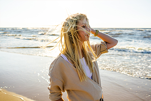 young woman in stylish clothing on seashore on summer day