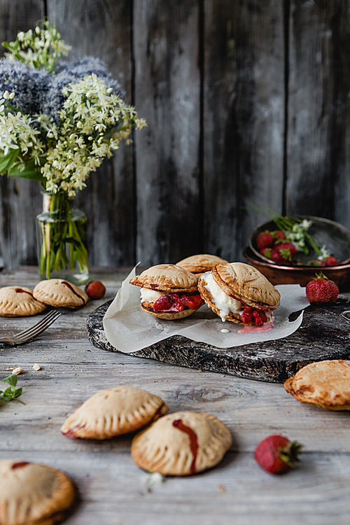 tasty cookies with strawberries on wooden table
